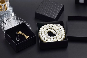 Detail view of premium black jewelry box with pearl necklace and gold pendant inserts