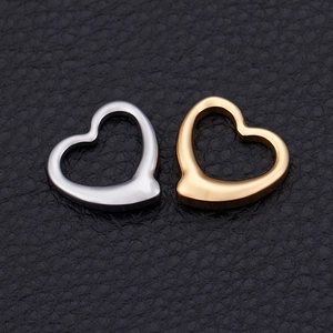 Polished gold and silver stainless steel open heart pendants on a textured leather surface