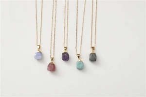 Detail view of five natural raw stone pendants on gold chains in various crystal types