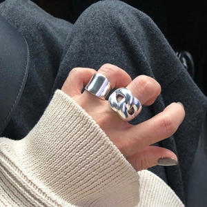 Detailed view of silver minimalist wide band and thick chunky chain rings on a hand