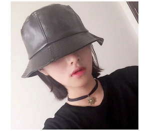 Detail view of stylish black PU leather bucket hat worn by model showing wide brim fit