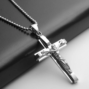 Close-up of a silver stainless steel Jesus cross pendant with a detailed bead chain necklace