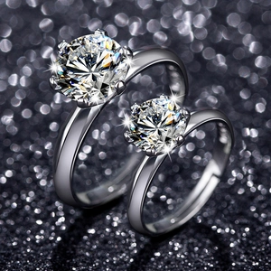 Close-up of two six-prong silver rings with brilliant round-cut stones on glitter background