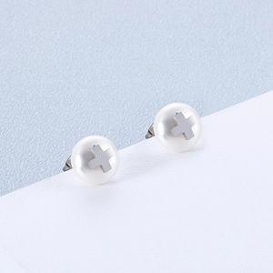 Minimalist pearl stud earrings with silver cross detail on a soft blue background