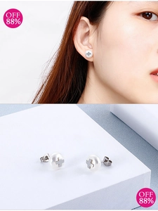 Detail of cross pearl earrings with metal butterfly clasp on a stone background