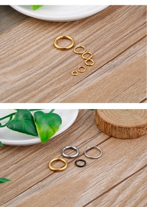 Close-up of gold, silver and black titanium steel open jump rings on wood surface