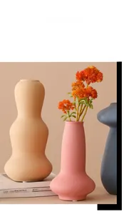 Dettaglio di vasi in ceramica opaca con finitura elegante e decorazione floreale arancione
