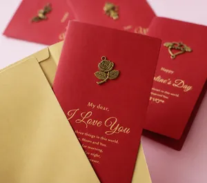 Detail of red textured card with vintage bronze rose metal charm and golden poem print