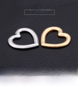 Polished stainless steel heart charm pendants in gold and silver on black leather texture