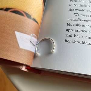 Close-up of S925 sterling silver open ring with double pearls set between book pages