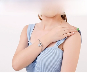 Détail du bracelet élégant en acier inoxydable avec breloque cœur et chaîne serpent au poignet