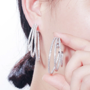 Three-layer silver hoop earrings with clear zircon stones worn by a model in a close-up