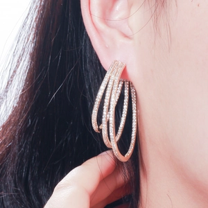 Close-up of triple-layered irregular rose gold zircon earrings worn by a model