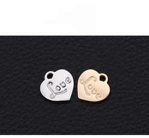 Detail of silver and gold heart pendants with Love engraving on black leather