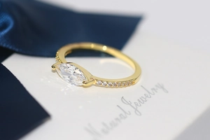 Macro shot of marquise-cut zircon ring with gold plating and paved stones detail