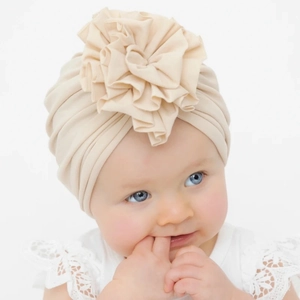 Soft and breathable baby turban hat featuring a large pleated flower in beige cotton