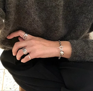 Close-up of 925 silver heart charm bracelet with OT clasp worn on a textured dark sweater
