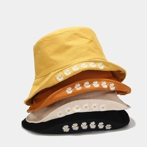 Primo piano di quattro cappelli a secchiello colorati con ricamo a margherita in vari colori