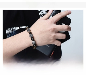 Detailed view of men's beaded bracelet featuring tiger eye stones and engraved steel beads