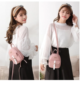 Lifestyle view of pink mini backpack with white straps and bow detail on a model