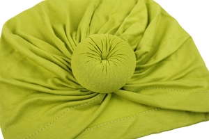 High-quality detail of the soft fabric donut knot on a lime green infant turban hat