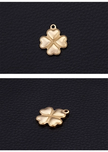 Macro shot of gold four-leaf clover heart pendants on black leather background