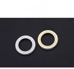 Détail macro de breloques circulaires en or et argent pavées sur cuir noir texturé