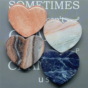 Close-up of heart-shaped marble texture phone stands in pink, beige, grey, and navy blue
