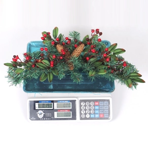 Weihnachtsdekoration mit Tannennadeln, roten Beeren und Zapfen auf weißer Waage
