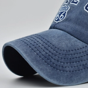 Macro detail of Route 66 embroidery and white stitching on washed blue cotton baseball cap