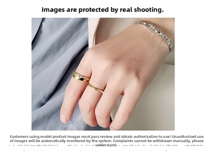 Close-up of golden twisted ring and bimetal band with silver chain bracelet on model hand