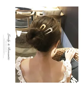 Detail showing U-shaped shell hair pin style on a model with warm cafe background
