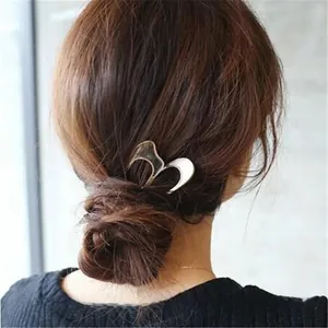 U-shaped metal hair fork with shell texture finish shown on an elegant low bun hairstyle