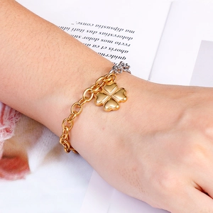 Gold-plated stainless steel four-leaf clover bracelet worn by a model on a wrist
