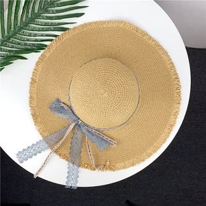 Straw sun hat with frayed brim and blue lace bow for summer beach travel and vacation