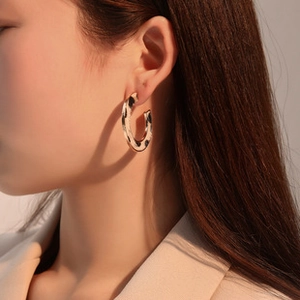 Close-up of vintage large C-shaped earrings with leopard pattern worn on ear