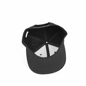 Internal detail of a black snapback cap showing 100% acrylic material and neat seams
