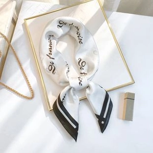 Detail of silk-like square scarf with elegant black letter print and rolled hem design