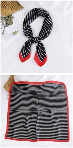 Detail of silk square scarf featuring black white stripes and elegant red borders