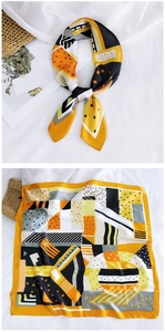 Detailed view of square silk scarf with yellow and black geometric patterns and knotted style