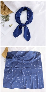 Detailed view of dark blue silk scarf featuring white seagull print and smooth texture
