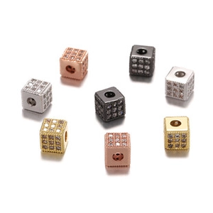 Macro detail of micro-pave zircon cube beads in gold and silver for jewelry making