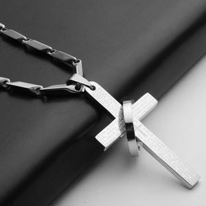 Close-up of stainless steel cross pendant with etched Spanish Lord's Prayer text
