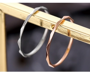 Macro shot of silver and rose gold polished faceted rings on a metal stand display
