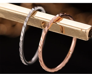 Vista macro di anelli in titanio argento e oro rosa su un supporto dorato