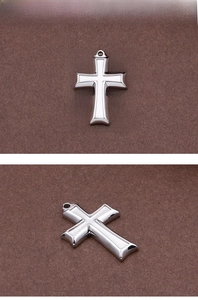 Detailed macro view of silver stainless steel cross pendant with polished finish texture