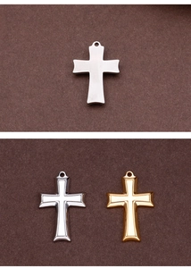 Detailed view of silver and gold stainless steel cross pendants on a dark surface