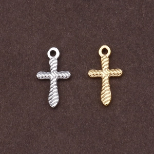 Vintage style gold and silver cross pendants with unique twisted texture on brown base