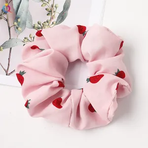 Detail of pink scrunchie with red strawberry print made of soft pleated fabric