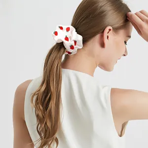 Close-up of a white fabric scrunchie with red strawberry print on a ponytail